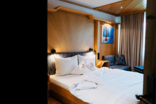a bedroom with a bed with white sheets and pillows at Pension Rudolph in Gaschurn