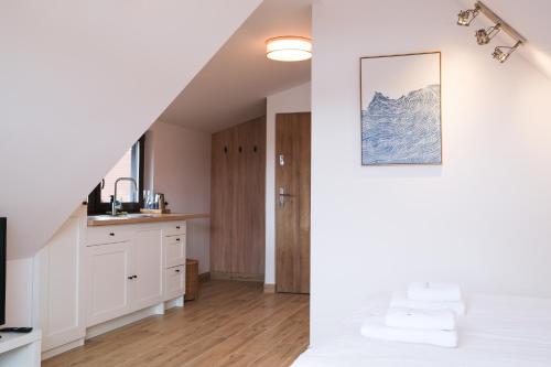 a bedroom with a white bed and a kitchen at MERSEA in Ustka