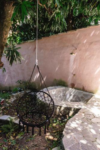 a swinging chair in a garden with a wall at Incrível Casa Colonial-Déco - Centro Histórico in Marechal Floriano