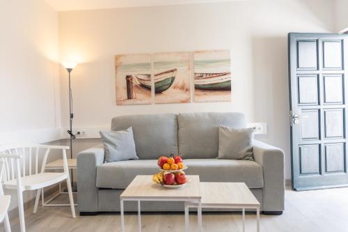 a living room with a couch and a table with fruit at Apartamentos Turísticos El Puerto de Comillas in Comillas