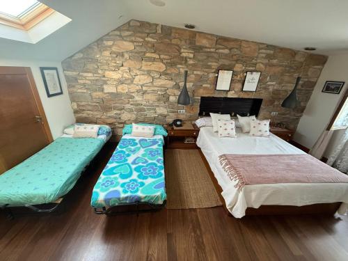 a bedroom with two beds and a stone wall at Finca Gonzalez in Deva