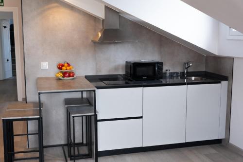 a kitchen with white cabinets and a counter with a microwave at Apartamentos Turísticos El Puerto de Comillas in Comillas
