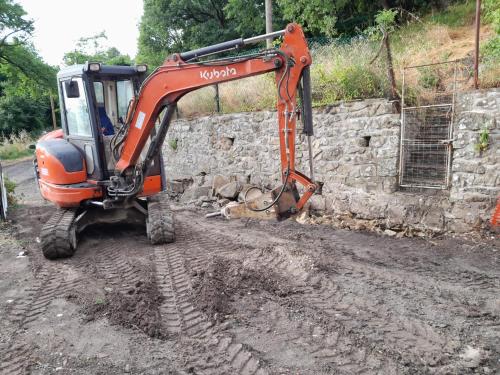 a bulldozer is parked next to a stone wall at La Quercia in San Benedetto Val di Sambro