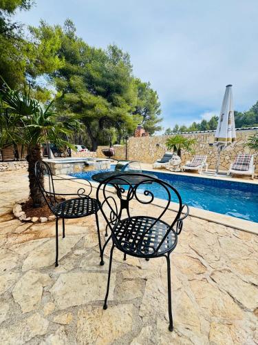 two chairs and a table in front of a pool at Villa Paradisio Ruheoase - Pool - Klima - Küche - Parken in Milna