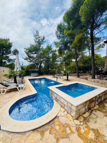 a large swimming pool with a stone walkway around it at Villa Paradisio Ruheoase - Pool - Klima - Küche - Parken in Milna