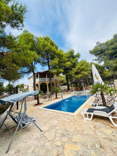 a pool with chairs and a table and a house at Villa Paradisio Ruheoase - Pool - Klima - Küche - Parken in Milna