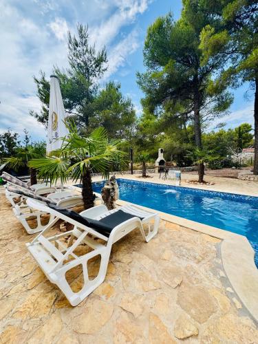 a group of lounge chairs next to a swimming pool at Villa Paradisio Ruheoase - Pool - Klima - Küche - Parken in Milna