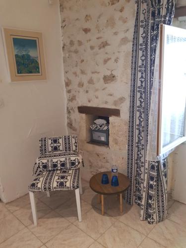 a room with a chair and a table and a window at Le gîte des chambres de la grange in Cherval