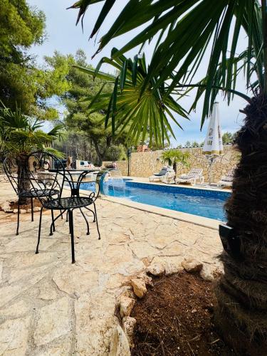 a patio with a table and chairs next to a pool at Villa Paradisio Ruheoase - Pool - Klima - Küche - Parken in Milna