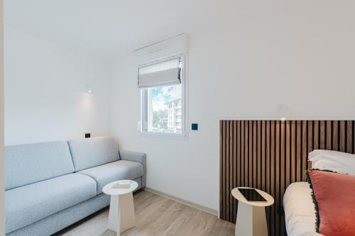 a living room with a blue couch and two tables at Appart Hotel Neostelia in Annecy