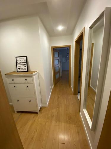 a hallway with a dresser and a mirror in a room at Nowy apartament OHIVI ŚWINOUJŚCIE in Świnoujście