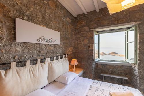 a bedroom with a stone wall with a bed and a window at Mykonos Mint Villa - Sofia in Kalafatis