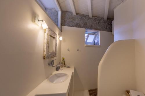 a white bathroom with a sink and a mirror at Mykonos Mint Villa - Sofia in Kalafatis