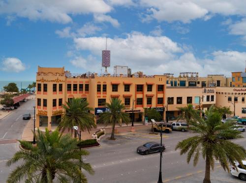 a city street with palm trees in front of a building at بفن للشقق المخدومة Puffin Serviced Apartments in Al Jubail