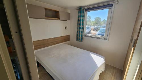 Una pequeña habitación con una cama y una ventana. en Mobile home Lacanau Ocean, en Lacanau