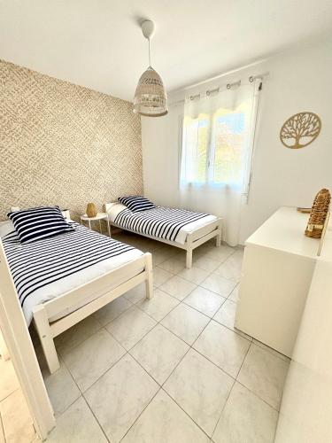 une chambre avec deux lits et une fenêtre dans l'établissement Chez Audrey - Charmante villa - Jardin & Clim, à Loupian