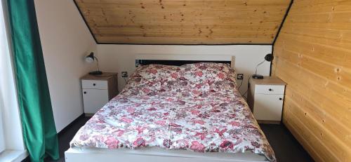 een slaapkamer met een bed met een bloemenbed bij Domek nad jeziorem Potoczek, Giże in Giże
