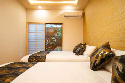 two beds in a room with a window at 葵宿-Aoiyado机场直达天下茶屋步行7分钟 in Osaka