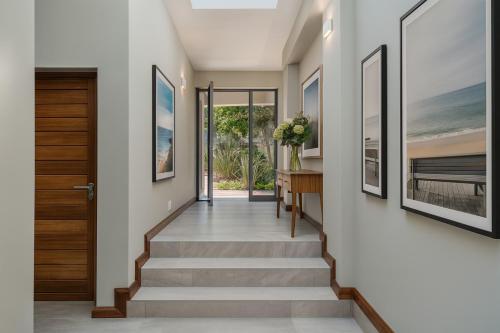 a hallway with stairs leading to a door with paintings at Haven Hill in Knysna
