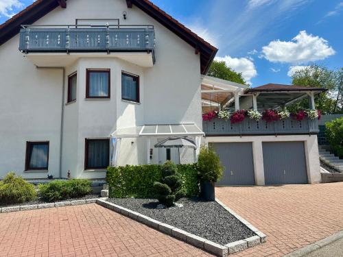 a white house with a balcony and a driveway at La Pura Vida in Bühlertann