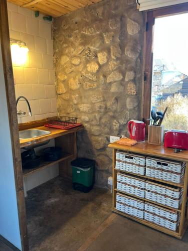 a kitchen with a stone wall and a sink at Cabañas El Legado in Los Molles