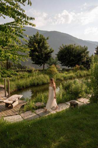 a woman in a white dress walking by a river at Naturhotel Lüsnerhof in Luson