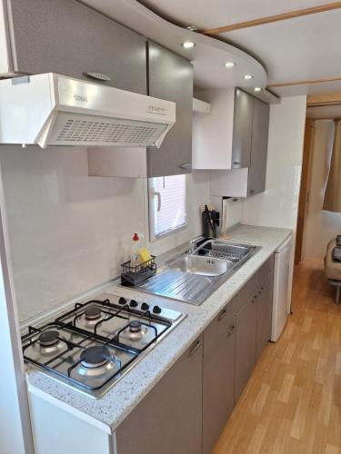 a white kitchen with a stove and a sink at Mobile home Magdalena in Pirovac