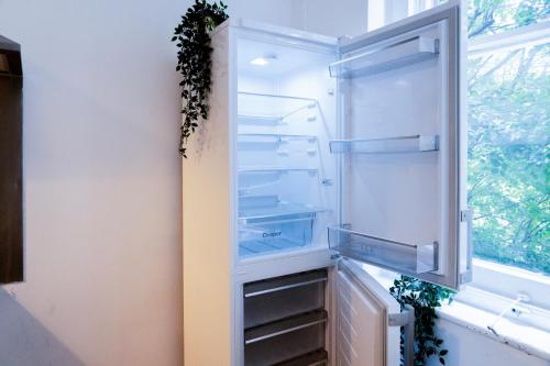 an empty refrigerator with its door open next to a window at London Bridge Stays in London
