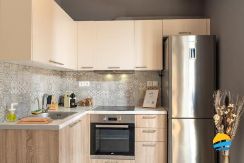 a kitchen with white cabinets and a stainless steel refrigerator at Pame Rentals - 2BD Modern Home Steps from Pasalimani in Piraeus