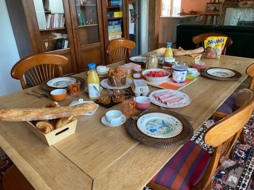 a wooden table with food and drinks on it at Domaine La Perruche Parenthèse poétique Vue Mont-Saint-Michel & Petit-déjeuner festin in Servon