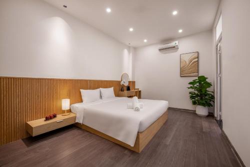 a bedroom with a large white bed and a plant at Aurora Villa - Near My Khe Beach & City Center by The Key in Da Nang