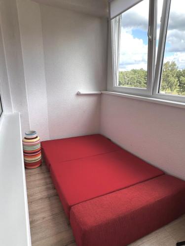 a red couch in a room with a window at Apartamentai Vanagupės banga in Palanga