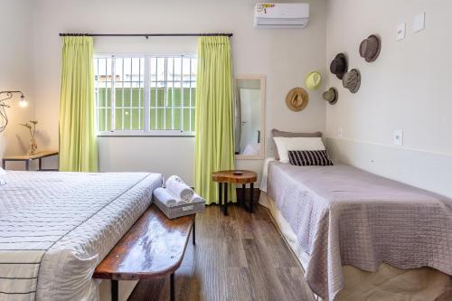 a bedroom with two beds and a window with yellow curtains at RESORT PARTICULAR perfeito p/ famílias com crianças e grupos in Foz do Iguaçu