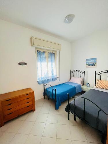 a bedroom with two beds and a window at Appartamento Fronte Mare Marzamemi in Marzamemi