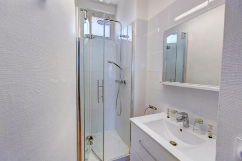 a white bathroom with a shower and a sink at Le Gîte de la Plage in Étretat