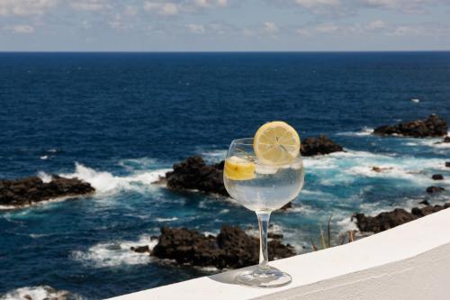 a glass of water with a lemon in front of the ocean at Sundaze in Fenais da Luz