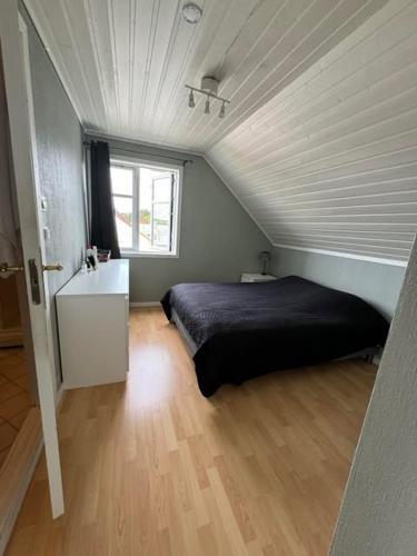 a bedroom with a black bed and a window at KSU Topleiligheten in Kristiansund