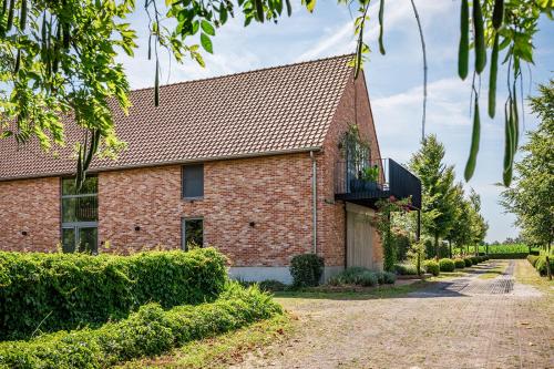 an old brick house with a balcony and a driveway at De Weldoeninge in Wingene