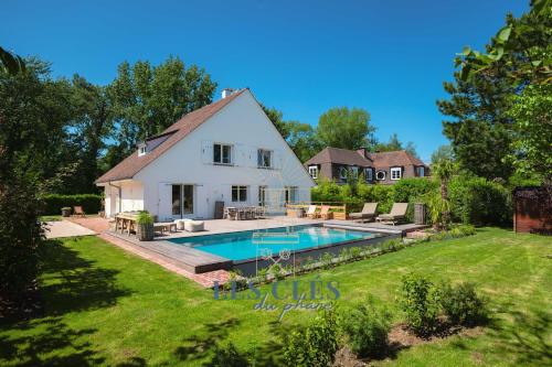 a white house with a swimming pool in the yard at Villa Los Cuatro, situé au cœur du Touquet in Le Touquet-Paris-Plage