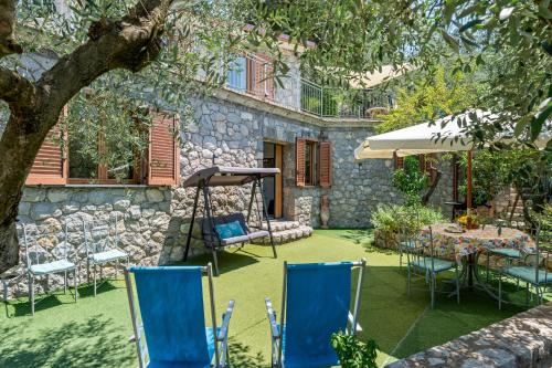 a patio with chairs and an umbrella and a table at Cynara holiday house in Massa Lubrense
