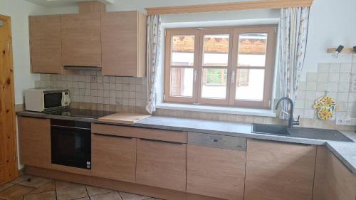 a kitchen with wooden cabinets and a sink and a microwave at Chalet Neuhofalm Obertauern mit Sauna und Hobbyraum in Obertauern