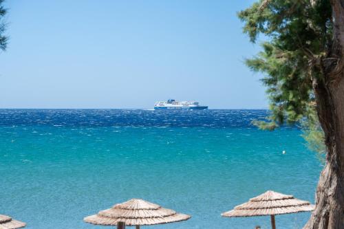 a cruise ship in the water with umbrellas on the beach at Notte di Mare in Kardiani
