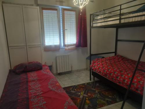 a bedroom with two bunk beds and a red bed at Petite maison du samedi au samedi in Biscarrosse