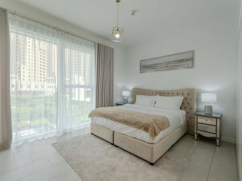 a bedroom with a bed and a large window at Jumeirah Beach Residences Private Beach & Sea View in Dubai