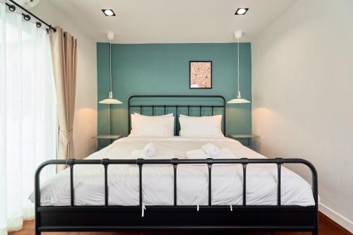 a bedroom with a bed with a blue wall at Emily Home-Charming 3BR in Chiang Mai Old Town, Steps from Wat Phra Singh & Sunday Walking Street by Beginning With in Chiang Mai