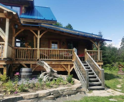 a log cabin with a staircase leading to a house at Gîte de l'herboriste in Sainte-Rose-du-Nord