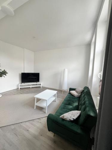 a living room with a green couch and a table at City Apartment in Magdeburg