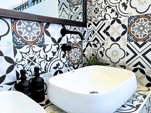 ein Badezimmer mit weißem Waschbecken und schwarz-weißen Fliesen in der Unterkunft A Casa Portuguesa Coron Boutique Hostel in Coron