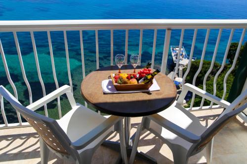 a table with a bowl of fruit and wine glasses on a balcony at Oasis Hotel in Perama