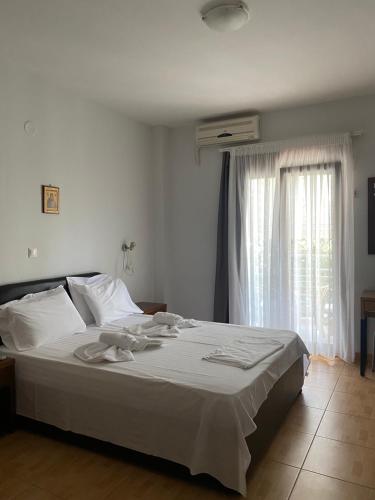 a bedroom with a bed with white sheets and a window at Hotel Magnolia in Loutra Edipsou